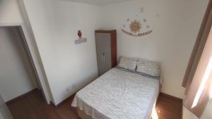 a small bedroom with a bed and a door at Apartamento Novinho Aeroporto JF in Juiz de Fora