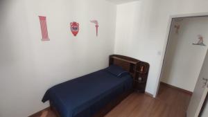 a small room with a bed with a blue bedspread at Apartamento Novinho Aeroporto JF in Juiz de Fora