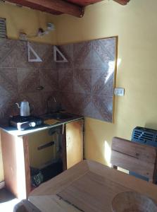 a kitchen with a stove and a table in a room at Cabañas la Casa del Tata in Potrero de los Funes