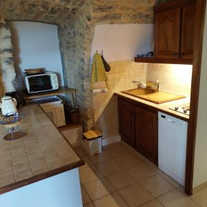 a small kitchen with a sink and a microwave at Mas de la Garrigue in Les Vans