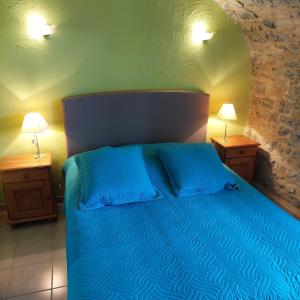 sypialnia z łóżkiem z niebieską pościelą i 2 lampami w obiekcie Mas de la Garrigue w mieście Les Vans
