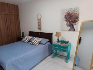 um quarto com uma cama e uma mesa com um abajur em Casa Laureles - San Joaquín em Medellín