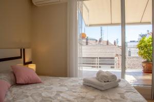 a bedroom with a bed with towels and a large window at BURGO NUEVO Ático de lujo en pleno centro con terraza y vistas - leonapartamentos in León