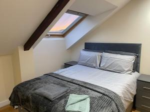 een slaapkamer met een bed met witte lakens en een raam bij The Orchards in Elland