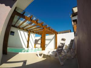 a patio with two chairs and a swimming pool at Residencial Viva Torres - Casas com 2 Dorms, Ar e Piscina Aquecida na Praia da Cal in Torres