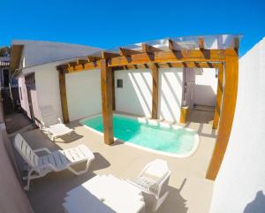 um pátio com uma piscina e cadeiras e uma pérgola em Residencial Viva Torres - Casas com 2 Dorms, Ar e Piscina Aquecida na Praia da Cal em Torres