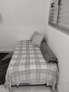 a bed with a plaid blanket and two pillows at Simples e Aconchegante in Mogi das Cruzes