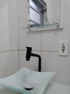 lavabo blanco en el baño con espejo en Simples e Aconchegante, en Mogi das Cruzes
