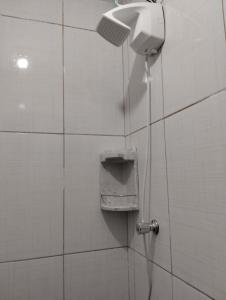 um chuveiro numa casa de banho em azulejo com uma mangueira em Simples e Aconchegante em Mogi das Cruzes