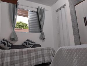 1 dormitorio con 2 camas y ventana en Simples e Aconchegante, en Mogi das Cruzes