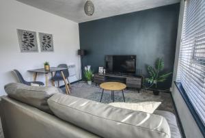 a living room with a couch and a tv at #2 Limes by DerBnB, Modern 1 Bedroom Apartment, Free Parking, WI-FI & Netflix Near Royal Derby Hospital in Derby