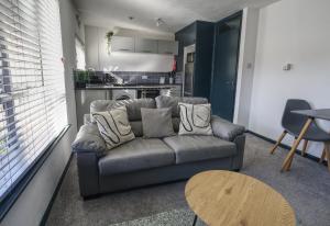 a living room with a couch and a table at #2 Limes by DerBnB, Modern 1 Bedroom Apartment, Free Parking, WI-FI & Netflix Near Royal Derby Hospital in Derby