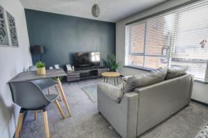 a living room with a couch and a table and a television at #2 Limes by DerBnB, Modern 1 Bedroom Apartment, Free Parking, WI-FI & Netflix Near Royal Derby Hospital in Derby