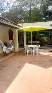 d'une terrasse avec une table, des chaises et un parasol jaune. dans l'établissement Sítio Alazão, à Moeda