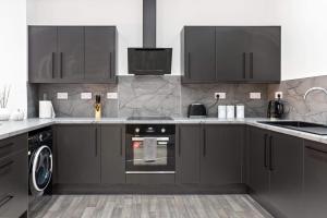 a kitchen with black cabinets and a dishwasher at Cowgate Luxury Apartments in Peterborough