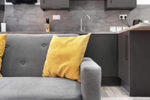 a gray couch with yellow pillows in a kitchen at Cowgate Luxury Apartments in Peterborough