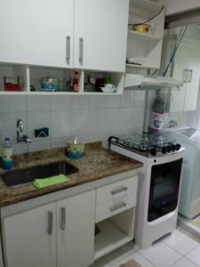 a kitchen with white cabinets and a sink and a stove at Espaço Sol, Mar & Cia in Bertioga