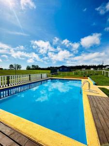 une grande piscine bleue avec une terrasse en bois dans l'établissement Cabañas Alto las Torres, à Los Ángeles