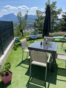 eine Terrasse mit einem Tisch, Stühlen und einem Sonnenschirm in der Unterkunft Appartement Cocooning entre lacs et montagnes in Saint-Alban