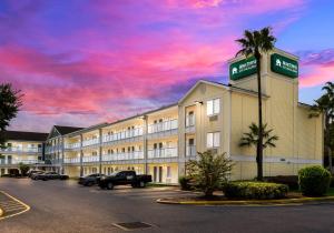 a hotel with cars parked in a parking lot at HomeTowne Studios by Red Roof Orlando - UCF Area in Orlando