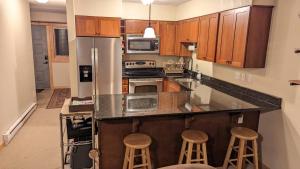 a kitchen with a stainless steel refrigerator and two stools at Cozy Townhouse on the main bus line in Breckenridge