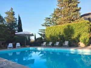 a swimming pool with chairs and an umbrella at Casa Dinda in Città di Castello