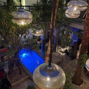 una piscina en un patio trasero con luces y árboles en Riad des Mile Nuits, en Marrakech
