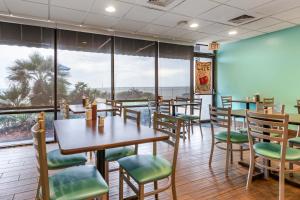a restaurant with tables and chairs and a large window at Tropical Winds Resort Hotel in Daytona Beach