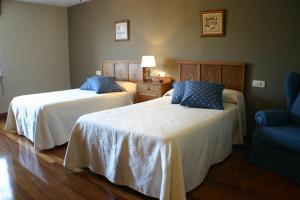 a bedroom with two beds and a blue chair at Fonte San Pedrín in Cajide