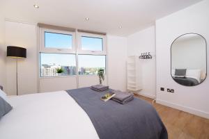 een witte slaapkamer met een groot bed en een spiegel bij Attractive London Apartment in Londen