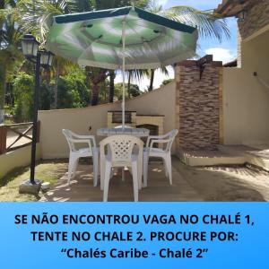 un patio con mesa y sillas bajo una sombrilla en Chalés Caribe brasileiro - Chalé 1, en Maragogi
