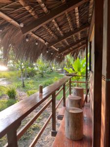 een houten veranda met 2 banken en een rieten dak bij Popochos Beach Eco-Lodge in Nuquí