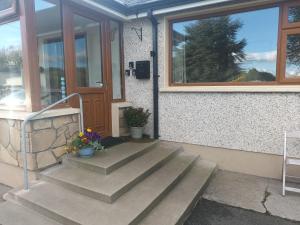 eine Haustür eines Hauses mit Treppen und Blumen in der Unterkunft Drumgauty Cottage in Strabane