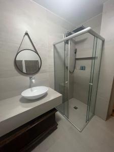 a bathroom with a sink and a shower with a mirror at Melhor Apto no Coração de BH com Garagem e Wi FI in Belo Horizonte