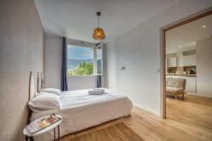 a bedroom with a bed and a large window at Le Lyon - Bastille / Esplanade in Grenoble
