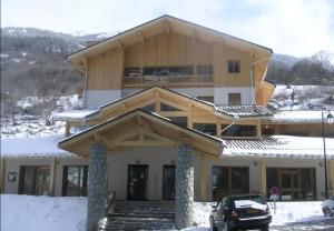 una gran casa de madera con un coche aparcado en la nieve en Les 3 vallées - Piscine/Spa/Hammam - 4p, en Orelle