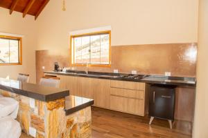 a large kitchen with a counter and a sink at Chalé Pedra Madeira in São Bento do Sapucaí