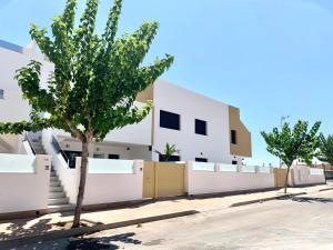 un edificio blanco con árboles delante de él en Casa flamenca, en San Pedro del Pinatar