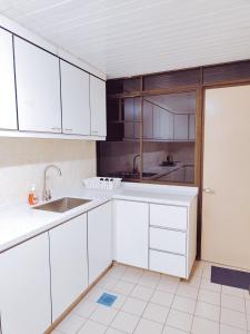 uma cozinha com armários brancos e um lavatório em Fahrenheit Pavilion By Cally Stay em Kuala Lumpur