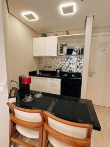 a kitchen with a black table and two chairs at Moema Times Square SP - Luxury Suíte in Sao Paulo