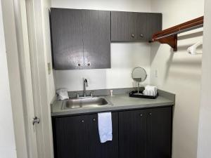 una pequeña cocina con lavabo y espejo en Desert Sands Inn & Suites, en Albuquerque