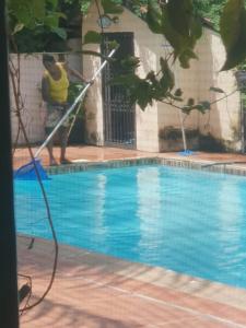 a man is washing a swimming pool with a hose at B & B Villa Calliandra in Bijilo