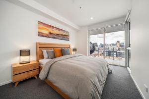 a bedroom with a bed and a large window at Ignite @ Park Tce Apartments in Adelaide