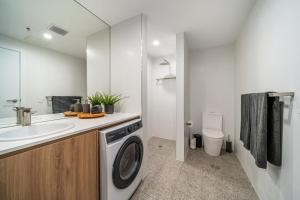 Un baño con lavadora y lavabo. en Ignite @ Park Tce Apartments, en Adelaida 38 fotos más