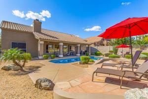 a house with a pool and a red umbrella at Desert Sojourn in Phoenix