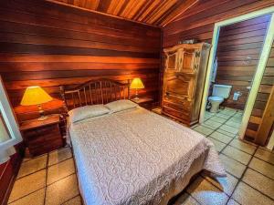 a bedroom with a bed and a wooden wall at UBATUBA, SP - BRASIL - PRAIA DO FELIX - Casa do Aconchego in Ubatuba