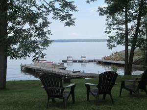 two chairs and a dock with boats on the water at Edgewater Motel and Campground in Temiskaming Shores