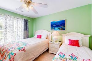 two beds in a bedroom with green walls and a ceiling fan at The Singing Gull in Myrtle Beach