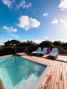 een zwembad op een houten terras met 2 ligstoelen bij Vila Real Apartamentos in Itacaré