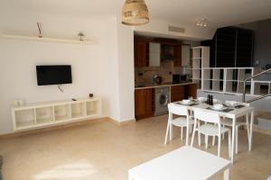 a living room with a table and chairs and a kitchen at Suite La Envía Golf in Almería